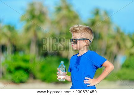 Portrait Of A Thirsty Handsome Boy In Sunglasses Drinking Water On The Desert Tropical Beach