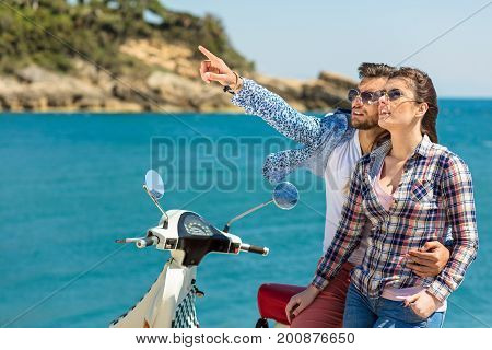 Couple sitting on motor scooter looking at each other.