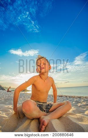 Handsome Eight Years Boy On Beach Performs Acrobatic Sketches And Plays With A Stream Of Sand