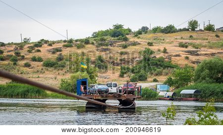 Ukraine Southern Bug River - 18 June 2017: Ferry crossing. The ferry moves with the help of a man's muscular strength. Repels from the steel cable. Such a ferry is unique in Ukraine.