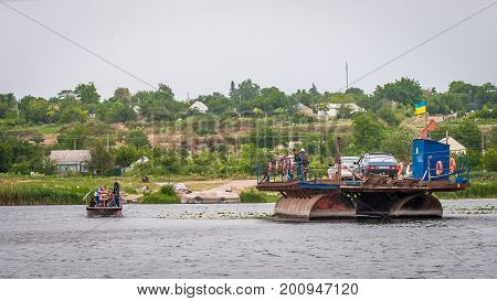 Ukraine Southern Bug River - 18 June 2017: Ferry crossing. The ferry moves with the help of a man's muscular strength. Repels from the steel cable. Such a ferry is unique in Ukraine.