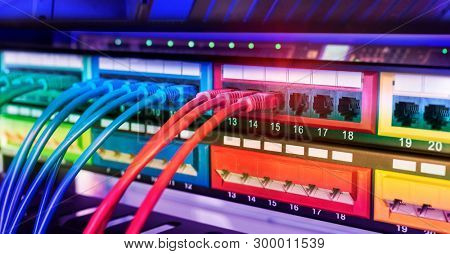 Server rack with blue and red internet patch cord cables connected to black patch panel in data server room