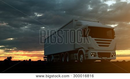 Large Freight Truck Driving On A Highway At Sunset Backlit By A Bright Orange Sunburst Under An Omin