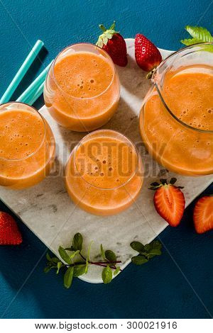 Strawberry Smoothies In A Carafe And Glasses On A Blue Background. Raw Breakfast