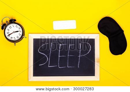 Sleep Concept Showing A Blackboard Spelling Sleep With An Alarm Clock, Sleeping Pills And An Eye Mas