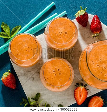 Strawberry Smoothies In A Carafe And Glasses On A Blue Background. Raw Breakfast
