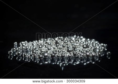 A Pile Of Pure Silver Granules. Isolated On Mirror Black Background. Selective Focus.