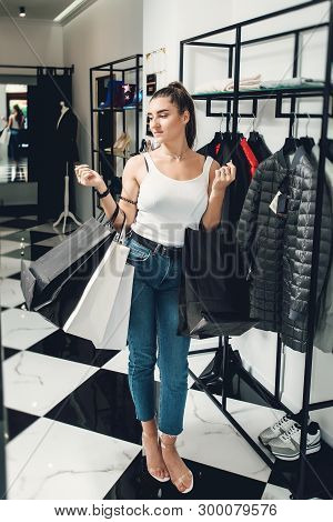 Smiling Girl Doing Many Purchases At The Clothing Shop. Woman With Packeges In Hands In A Clothing B