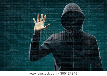 Computer hacker in mask and hoodie over abstract binary background. Obscured dark face. Data thief, internet fraud, darknet and cyber security.