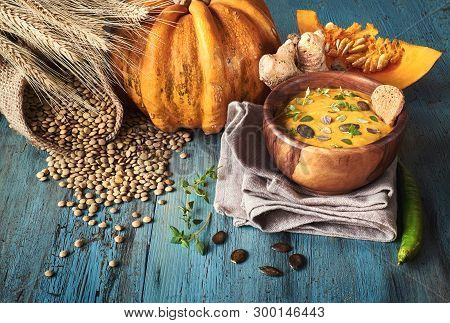 Pumpkin And Lentil Creme Soup Served In Olive Wood Bowl With Thyme Leaves And Pumpkin Seeds On Dark 