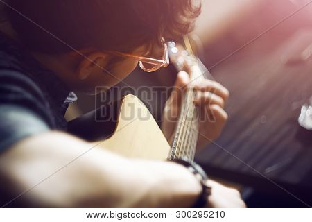 A Curly-haired Inspired Guy In A Shirt And Pink Glasses Plays A Melody On An Acoustic Guitar, Illumi