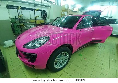 Moscow, Russia - May 09, 2019: Porsche Macan in service center, car wrapping, putting pink vinyl foil or film on car.