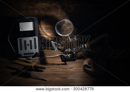 Retro Analog Voltmeter, Soldering Iron, Ram Module, Pliers And Screwdriver In The Light Of Lamp On A