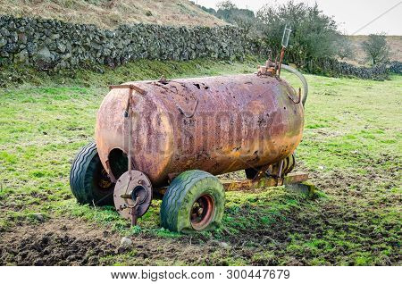 A Disused And Dilapidated Slurry Tanker With Punctured Tyres Sits Abandoned In A Muddy Field In The 