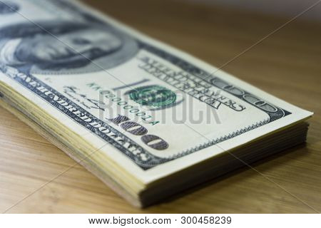 Crolled Stack Of 100 New Dollar Bills On Wooden Background