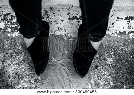 Women Legs Or Female Legs Shod In Black Colored Shoes And Blue Colored Jeans.