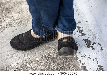 Women Legs Or Female Legs Shod In Black Colored Shoes And Blue Colored Jeans.