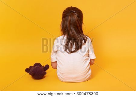 Little Girl Sitting Backwards With Brown Teddy Bear, Toddler Wearing White T Shirt Offended By Someo
