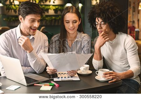 Millennial Business Team Discussing Project In Cafe, Reading Contract Terms And Conditions During Bu