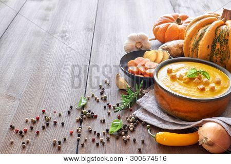 Pumpkin Creme Soup With Carrot And Ginger In Ceramic Bowl On Wood, Seasoned With Croutons And Basili