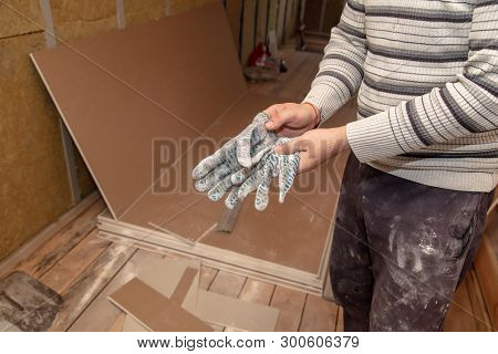 Worker Takes Off Gloves From Hands At A Construction Site.