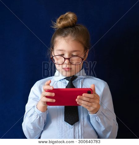 Elementary Grade Student Holding Smartphone. Expressionless Schoolchild In Uniform And Spectacles Ch