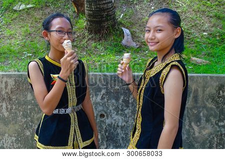 Labuan,malaysia-may 12,2019:kadazandusun Girls In Traditional Costume,eating Ice Cream During Hot Da
