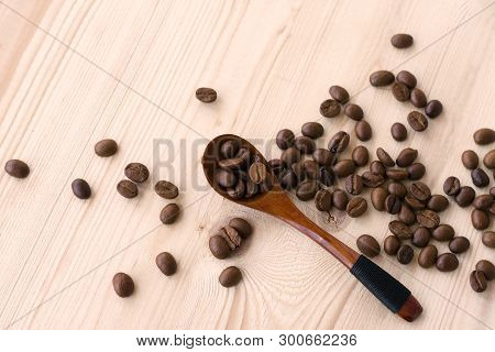 Roasted Coffee Beans In A Wooden Spoon N Table