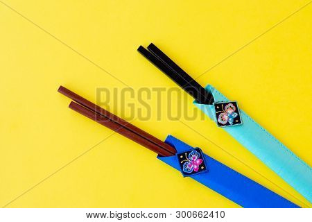 Two Different Colors Of Wooden Chopsticks Made Of Bamboo In Cases On Bright Yellow Background