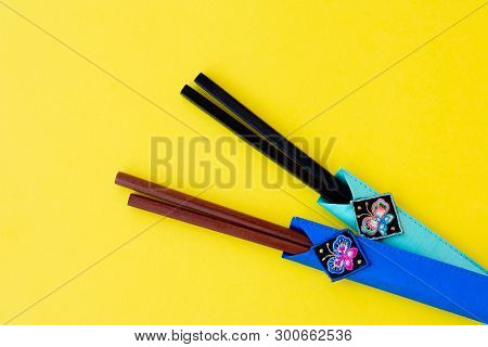 Two Different Colors Of Wooden Chopsticks Made Of Bamboo In Cases On Bright Yellow Background