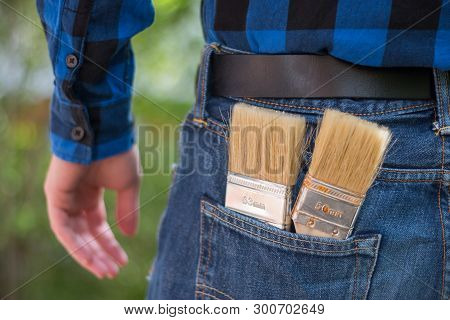Home Handyman: Rear View Of A Young Man With Paint Brushes In His Pocket