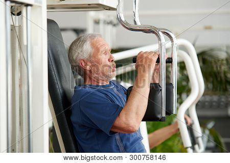 Senior Man Training On Butterfly Fitness Machine. Side View Senior Man Doing Chest Exercise On Machi