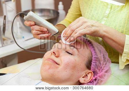 A Young Girl Is Lying On Couch With A Pink Hat On Her Hair While Performing An Ultrasonic Face Clean