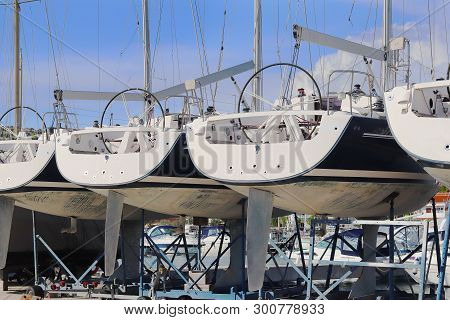 Same Yachts Stand In A Row On The Dry Parking In The Marina On A Sunny Summer Day. Device Sailing Ve