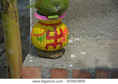 Close Up Of A Earthen/clay Pot In Yellow Color And Sign Of God Laxmi In Red Color Put On Mud Pad And