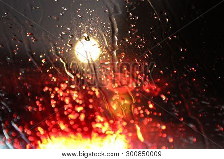 Traffic Is Viewed Through The Car's Windshield Covered In Rain, . Beautiful Background Of Rain And L