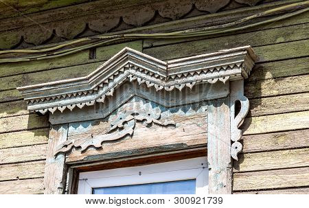 Russian Traditional Wooden Architecture. Facade Of An Old House Decorated With Wooden Carvings, Plat