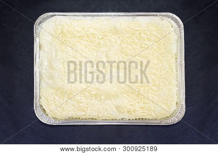 Pre-cooked Cold Lasagne Foil Tray. Isolated Over Black Slate Board