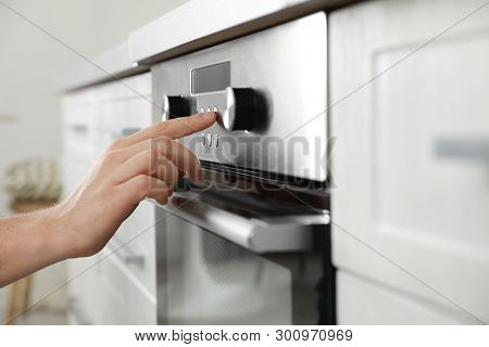 Man Regulating Cooking Mode On Oven Panel In Kitchen, Closeup