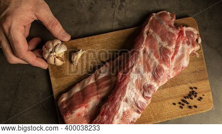 Fresh Pork Ribs, Cooking For Frying With Garlic, On A Wooden Background Top View. Mens Hands Hold Ga