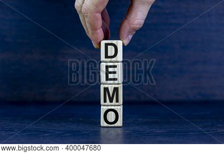 Demo Symbol. Concept Word 'demo' On Cubes On A Beautiful Dark Wooden Background. Businessman Hand. B