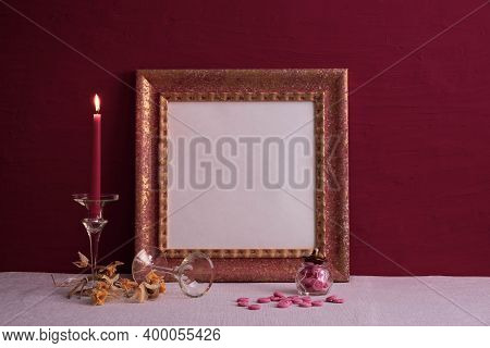 Dry Daffodils, A Long-stemmed Candlestick And A Candle Burning, An Old Photo Frame On Red And A Deco