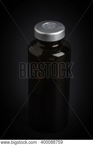 A Macro Shot With Selective Focus Of An Amber Color Vaccine Injection Bottle Set On A Dramatic Black