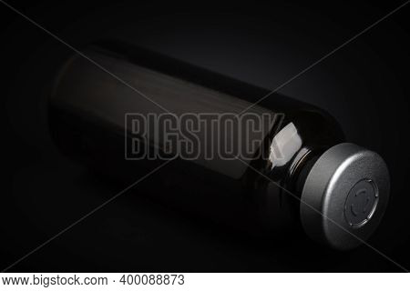 A Macro Shot With Selective Focus Of An Amber Color Vaccine Injection Bottle Set On A Dramatic Black
