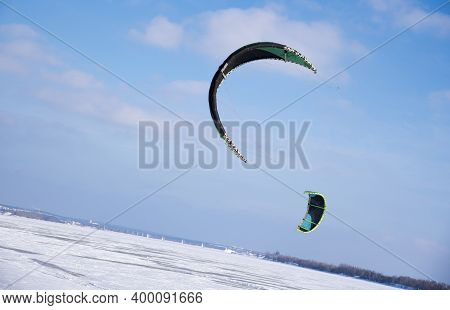Paragliders In Blue Sky At Winter Over Frozen River. Snow Kiting. Winter Sports. Sloping Horizon