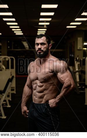 Strong Young Bearded Caucasian Man With Perfect Sport Physique Body In Dark Fitness Bodybuilding Gym