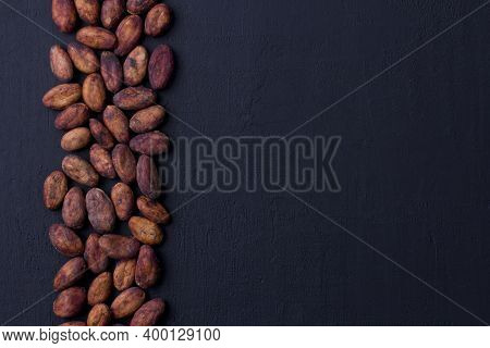 Unpeeled Raw Brown Cocoa Beans In Heap Lie On Black Modern Concrete Background. Flat Lay, Mock Up, C