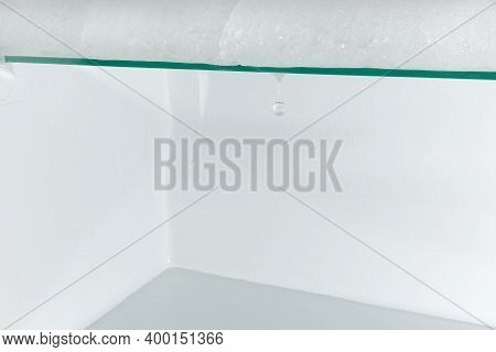 Melting Ice On The Glass Shelf Of The Frige With A Drop Of Falling Water