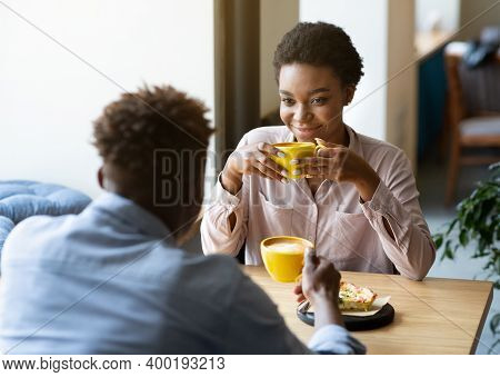 Handsome Black Man With His Girlfriend Enjoying Aromatic Coffee And Having Friendly Conversation At 