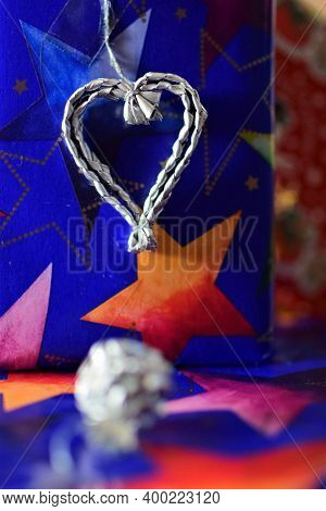 Close Up Of Colorful Christmas Gifts With A Silver Colored Heart And Strawball
